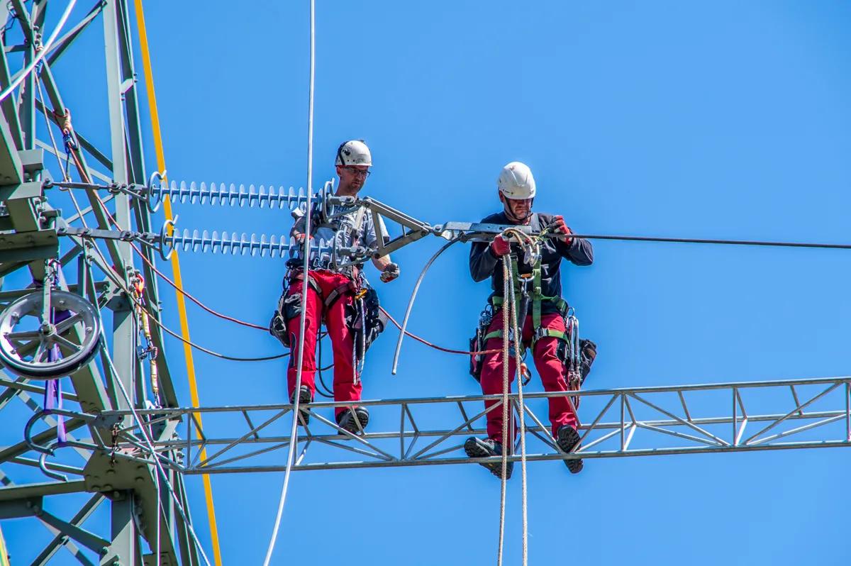 zwei Mitarbeiter bei der Arbeit auf einem Freileitungsmasten