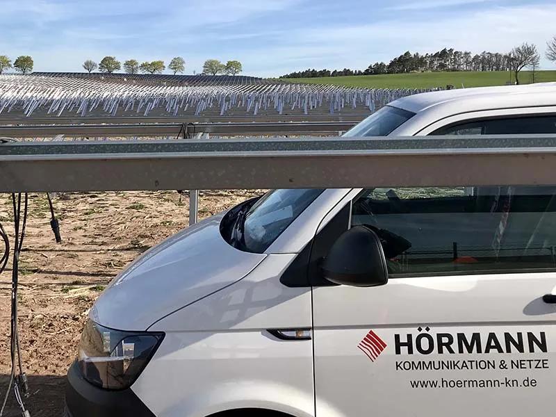 PV-Anlage mit Fahrzeug mit der Aufschrift "HÖRMANN Kommunikation & Netze" im Vordergrund
